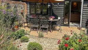 Un patio con posti a sedere all'aperto, tetto in tegole e area giardino con diverse piante.