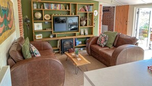 Un accogliente soggiorno con camino, divani in pelle, una TV e una libreria piena di libri e oggetti decorativi.