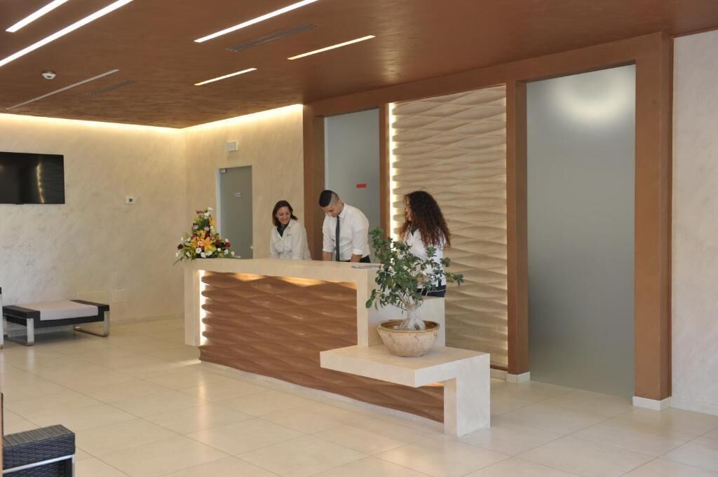 A reception area with a wooden reception desk, a potted plant, and a wall-mounted TV.