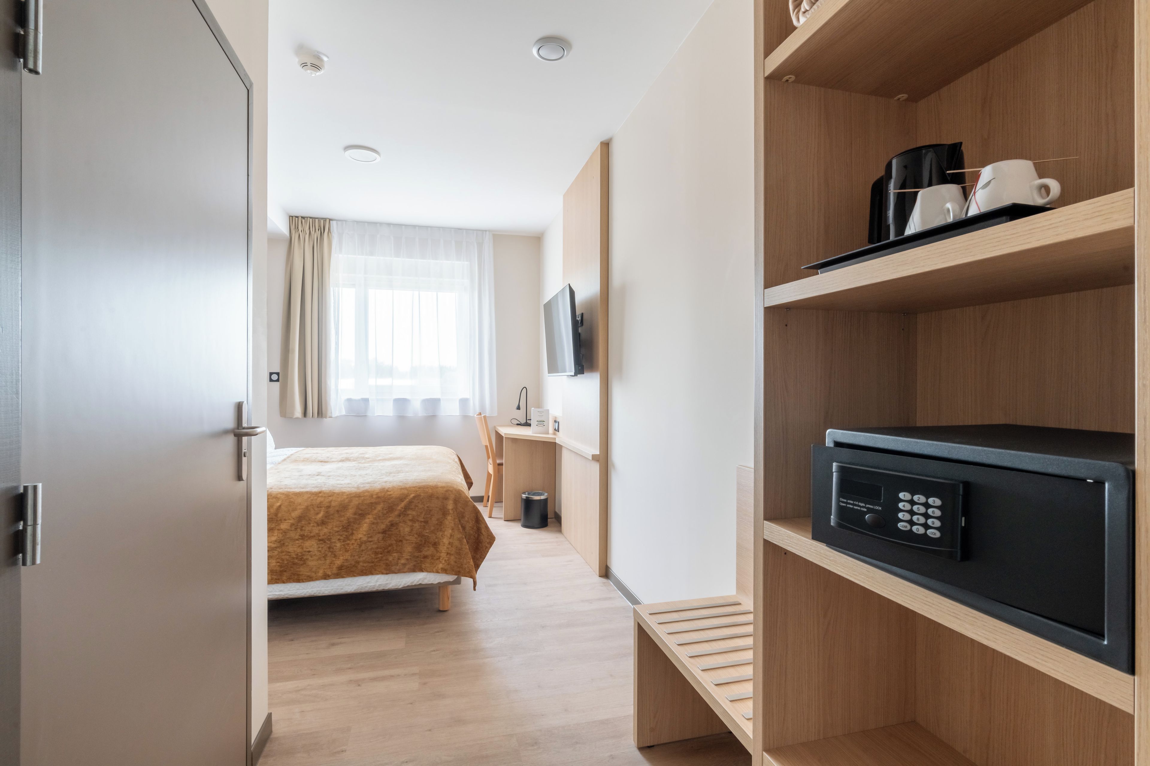 Una camera d'albergo con un letto, una scrivania, una televisione e un piccolo frigorifero.