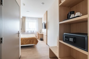 Una habitación de hotel con cama, escritorio, televisor y minibar.