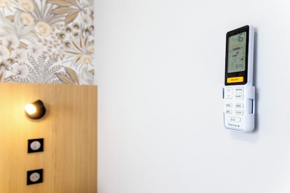 Termostato fijado a la pared, con pantalla digital, botones de control y un interruptor de alimentación.
