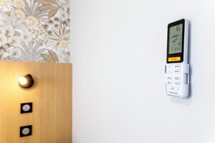 Termostato fijado a la pared, con pantalla digital, botones de control y un interruptor de alimentación.