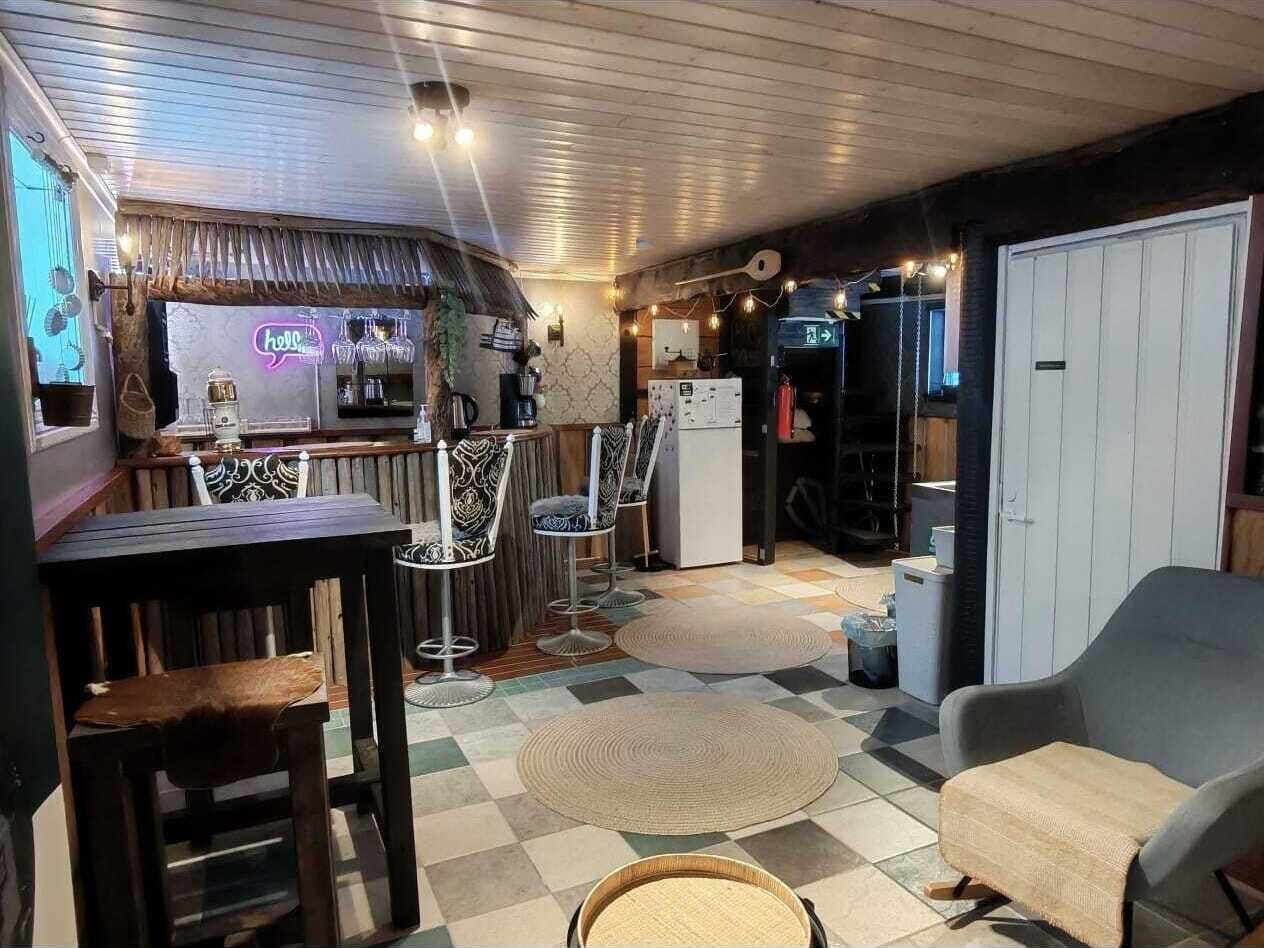 A cozy, well-lit room with a bar area, seating, and a kitchen.
