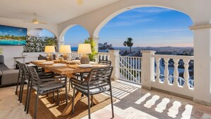 A dining area with a table set for four, a ceiling fan, and a view of the city. - Amazing villa los pajaritos with stunning views - Ref 50 (Las Lagunas de Mijas)