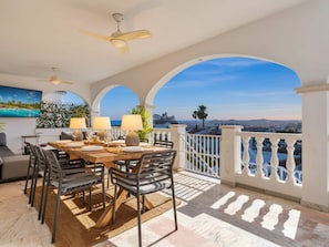A dining area with a table set for four, a ceiling fan, and a view of the city. - Amazing villa los pajaritos with stunning views - Ref 50 (Las Lagunas de Mijas)