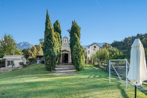 A residential property with a stone pathway leading to a white building with a bell tower, surrounded by tall cypress trees and a mountain backdrop. - The Rural Hostel in Mombeltrán, Ávila, Tiétar Valley (Mombeltrán)