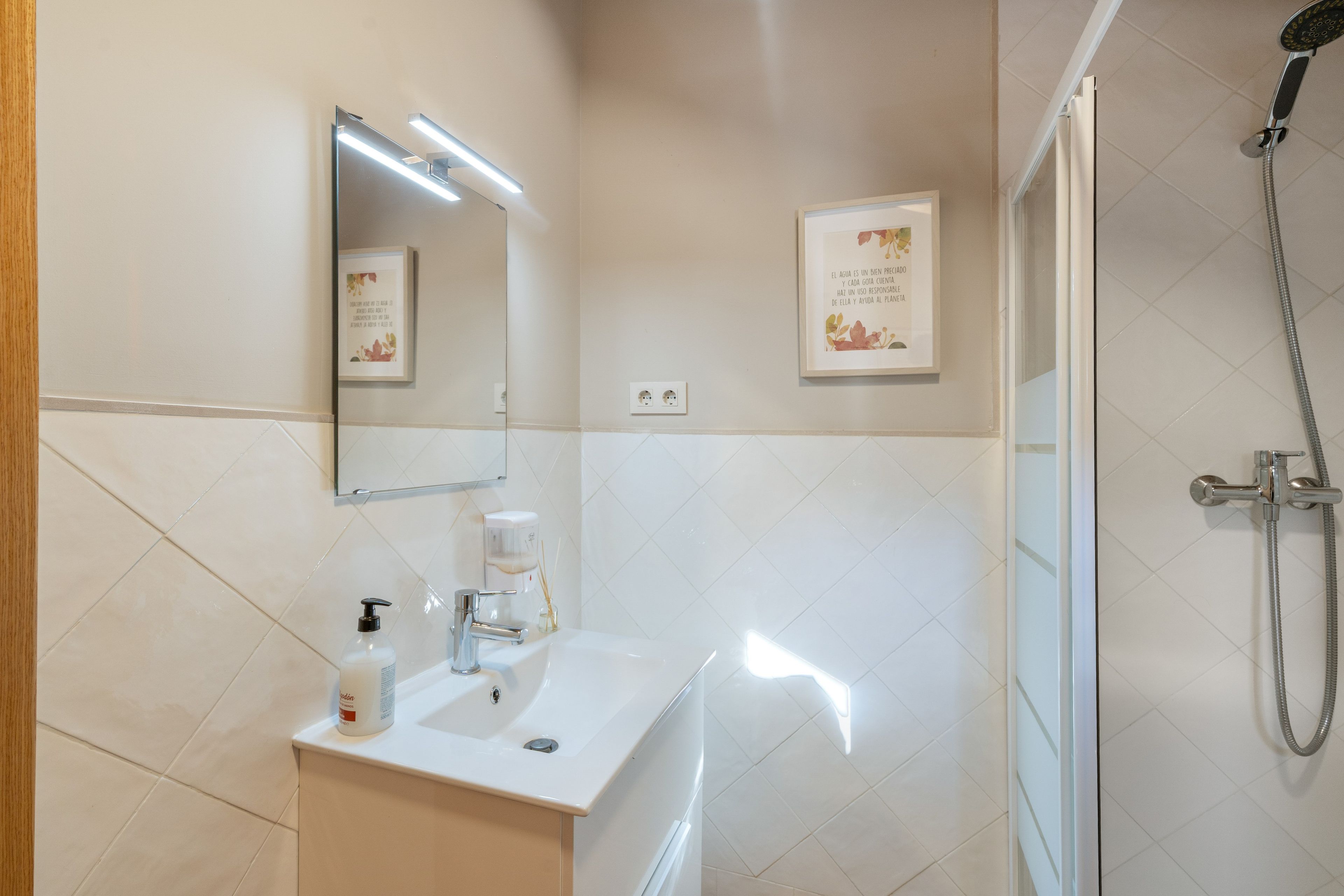 Un baño con lavamanos, espejo y ducha.