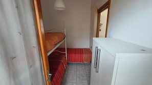 A small, narrow room with a bunk bed, a white cabinet, and a door leading to another room. - Beachside Apartment With Parking (Rosolina)