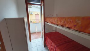 Pieni huone, jossa on kerrossänky, vaatekaappi ja ovi, joka johtaa parvekkeelle.