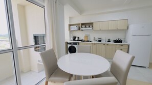 Een moderne keuken met een ronde tafel en stoelen, een wasmachine en een koelkast.