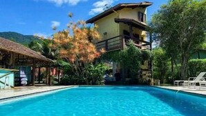 A clear blue pool with a building in the background. - Cabanas Mountain (São Sebastião)