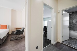 A bedroom with a bed, a desk, and a chair. There is a bathroom with a bathtub and a shower. - 6-bed Manchester Holiday (Manchester)