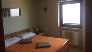 Makuuhuoneessa on puinen sänky, ikkuna, patteri ja seinälle kiinnitetty peili.