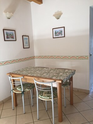 A dining area with a wooden table and four chairs, a decorative border on the wall, and two framed pictures. - House MARGHERITA - apartment 2 (Brenzone sul Garda)