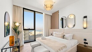 Quarto de hotel moderno com uma cama grande, uma escrivaninha e vista para a cidade.