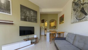 A living room with a TV, sofa, and artwork on the walls. - Atelier Vella by Interhome (Scarlino)