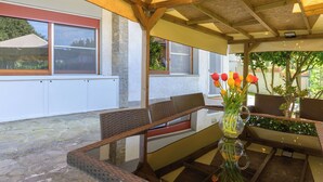 An outdoor patio with wicker furniture, a glass table, and a vase with flowers. - Atelier Vella by Interhome (Scarlino)