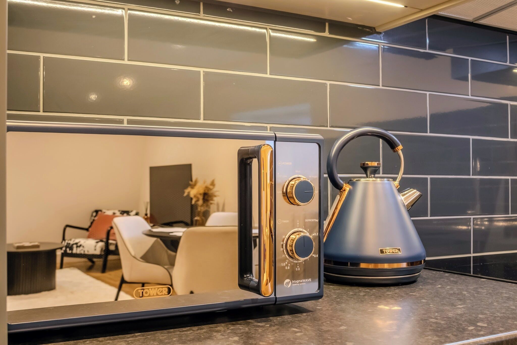 A modern kitchen with a built-in microwave, a kettle, and a coffee maker.