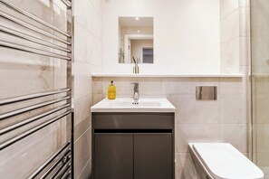 A bathroom with a white sink, a mirror above it, and a toilet. - Stylish Flat, Family Friendly, Walk to The Oracle (Reading)