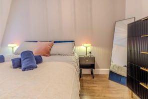 A bedroom with a bed, two bedside tables with lamps, a mirror, and a wardrobe. - Stylish Flat, Family Friendly, Walk to The Oracle (Reading)