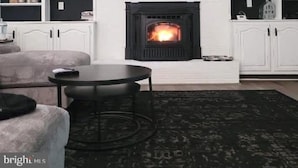 Un salon avec une cheminée, des meubles blancs et un tapis noir.