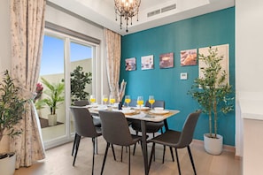 Un comedor con una mesa dispuesta para cuatro personas, rodeada de sillas, y vistas al exterior.