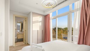 A hotel room with a large bed, a balcony with a view, and a bathroom with a sink and mirror.