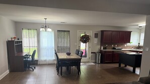 A spacious living area with a dining table, chairs, and a kitchen area with wooden cabinets and a countertop. - Perfect 3-bedroom house with 2-car garage,AC and heat in welcoming Ponchatoula (Ponchatoula)