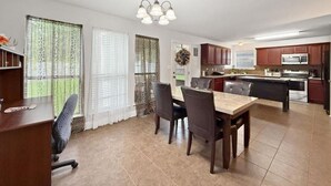 A modern kitchen with dark cabinets, a central island, and a dining area with a table and chairs. - Perfect 3-bedroom house with 2-car garage,AC and heat in welcoming Ponchatoula (Ponchatoula)