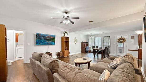 A spacious living room with a large sectional sofa, a dining area with a table and chairs, and a ceiling fan. - Perfect 3-bedroom house with 2-car garage,AC and heat in welcoming Ponchatoula (Ponchatoula)