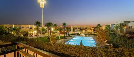 A pool area with a view of a building complex at dusk.