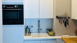 A compact kitchen with a built-in oven, a sink, and a knife rack. - Studio Oostende Dichtbij Strand Centrum (Ostend)
