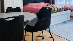 A compact hotel room with a bed, a small table, and two chairs. - Studio Oostende Dichtbij Strand Centrum (Ostend)