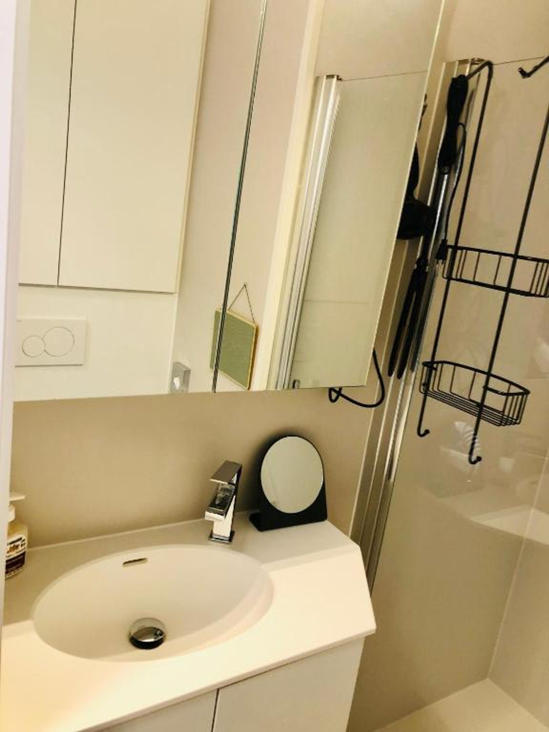 Un baño con un lavamanos blanco, un espejo y una cabina de ducha de vidrio.