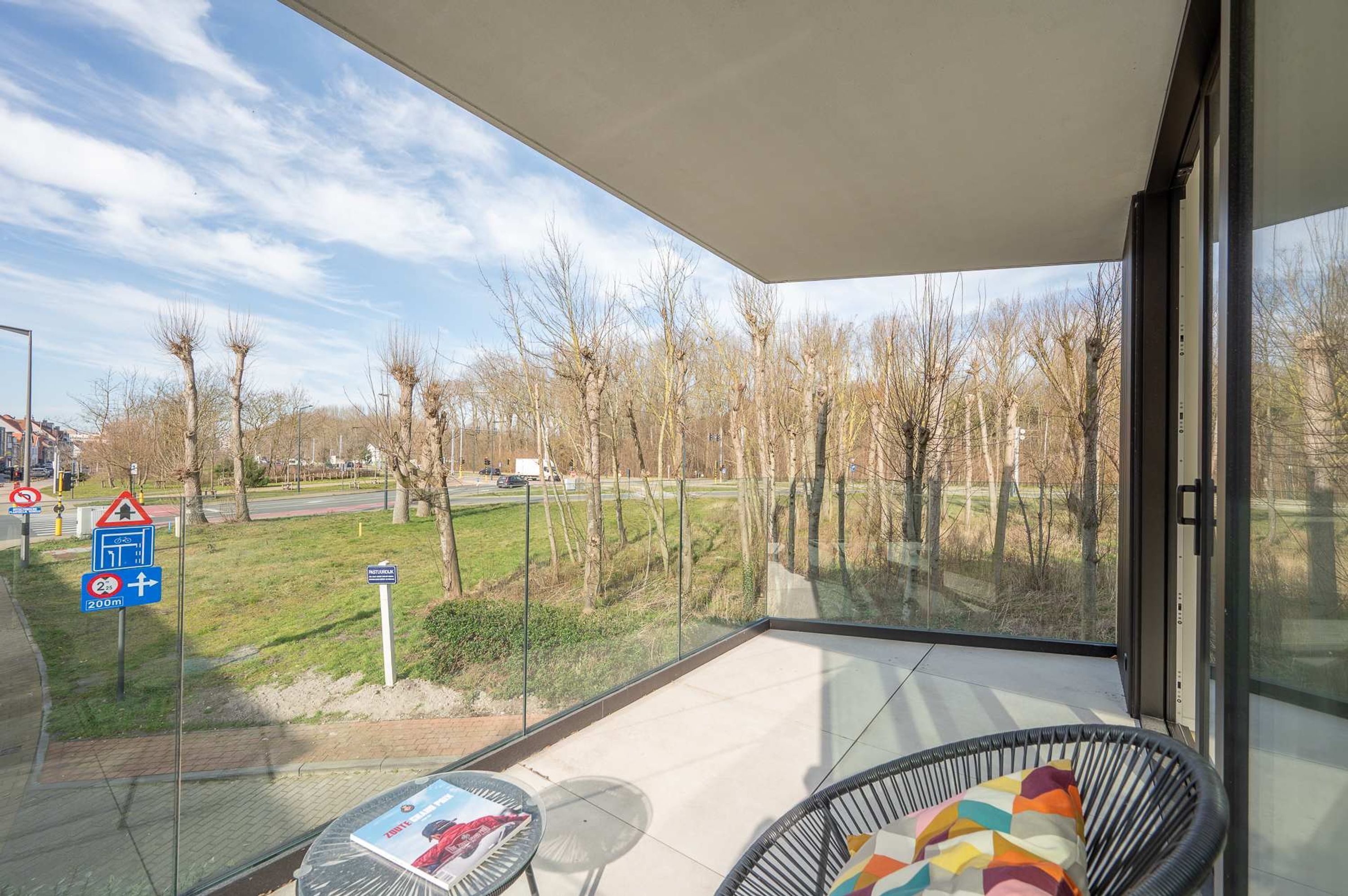 A balcony with a glass door, a chair, and a table.