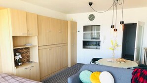 A compact room with a bed, a sofa, a small table, and a kitchenette in the background. - Zeezicht Studio Alisa (Blankenberge)