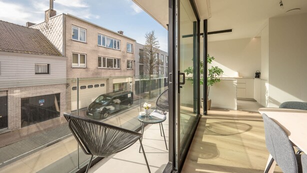 A modern apartment with a balcony, a kitchen area, and a view of the street. - Levant Appartement 2 Slaapkamers 2 Badkamers Balkon Knokke-heist (Knokke-Heist)