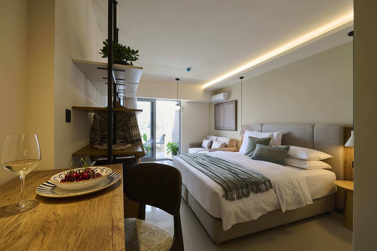 Une chambre à coucher comprenant un lit, une table de chevet, une lampe, ainsi qu’un coin repas avec une table et une chaise.