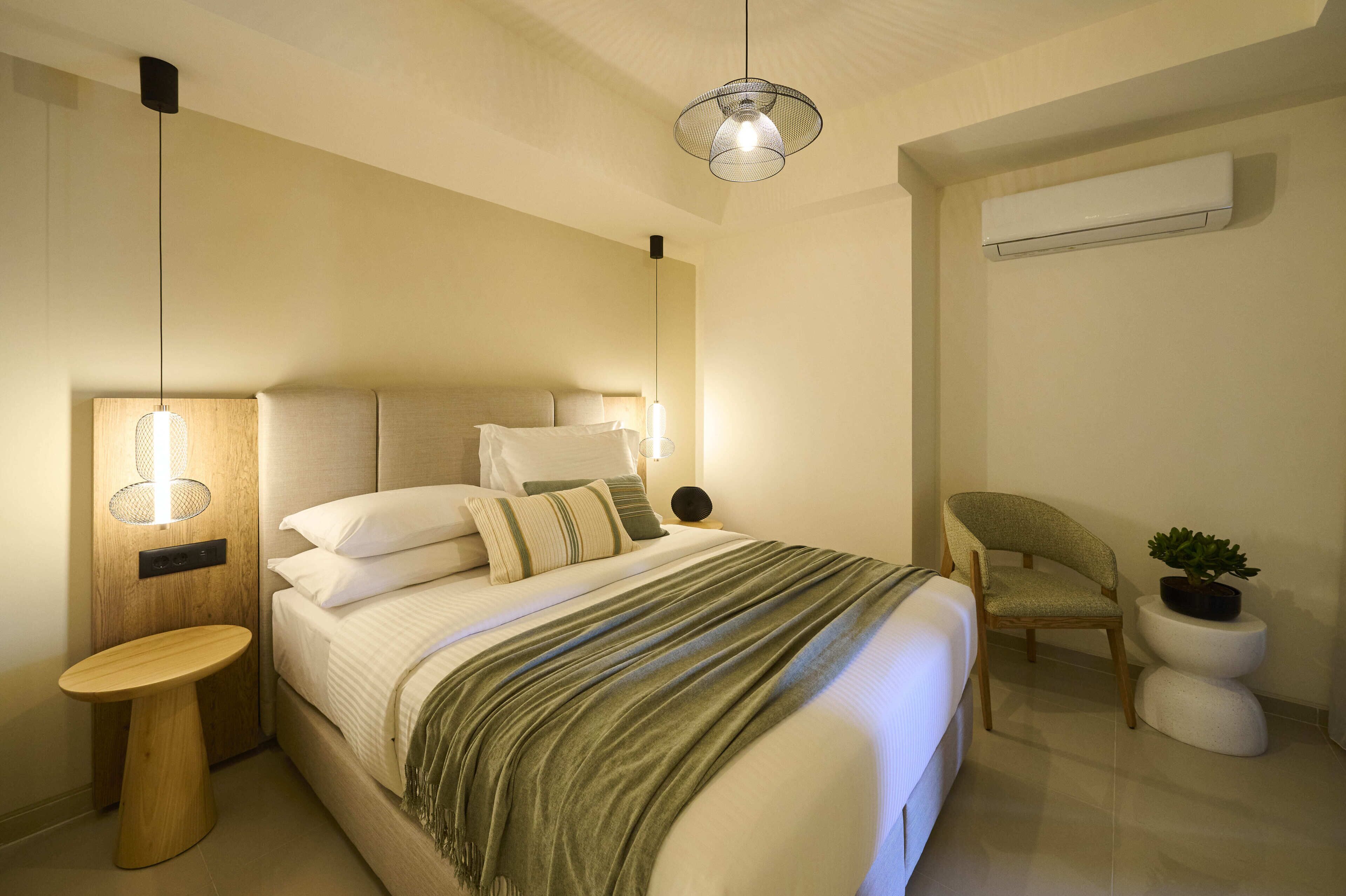 Un dormitorio moderno con cama, mesita de noche, silla y aire acondicionado de pared.