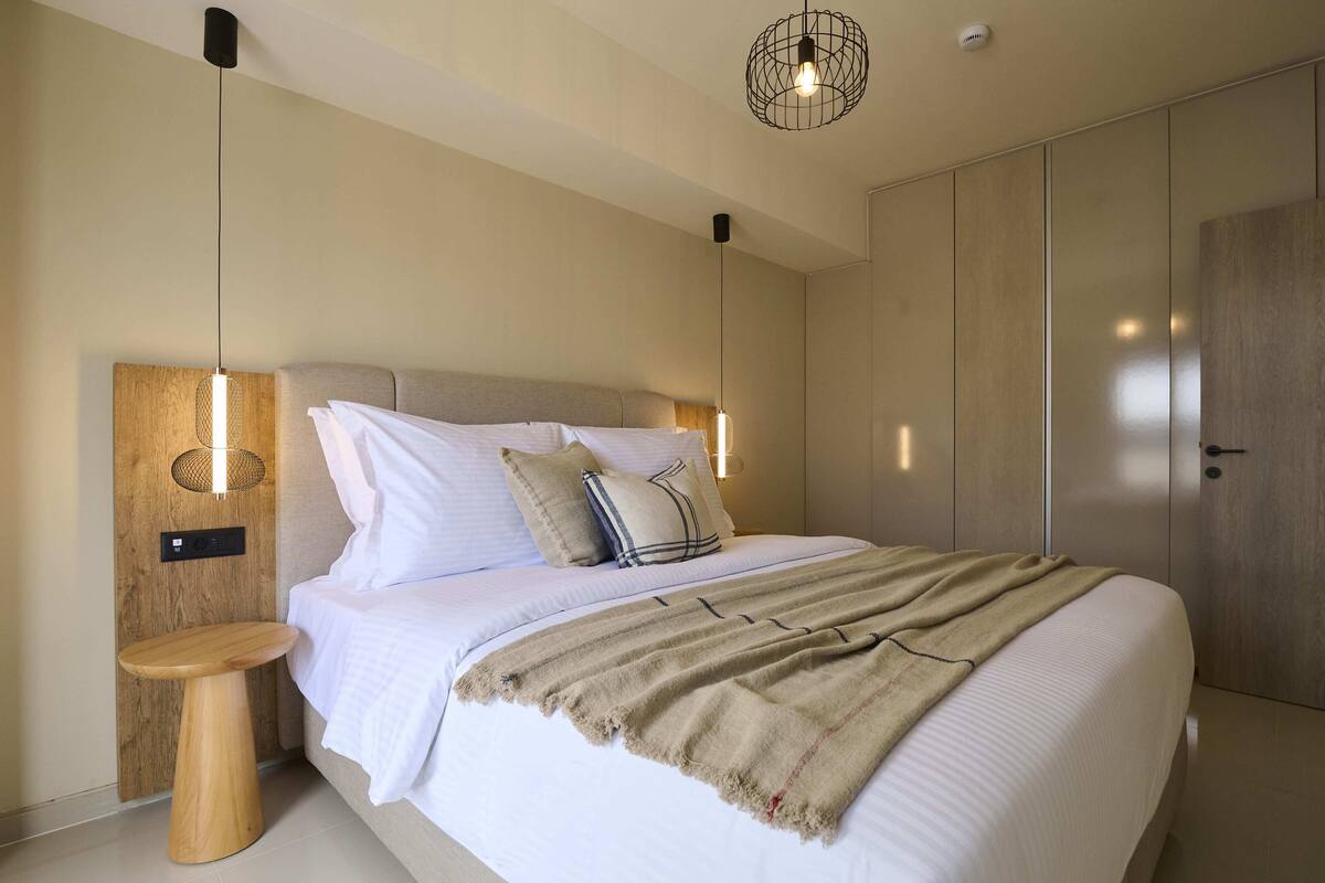 Une chambre moderne comprenant un lit, une table de chevet, une lampe fixée au mur et une armoire.