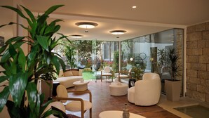 A modern living room with a glass wall, white furniture, and a large plant. - Zeus Piraeus Grand (Piraeus)