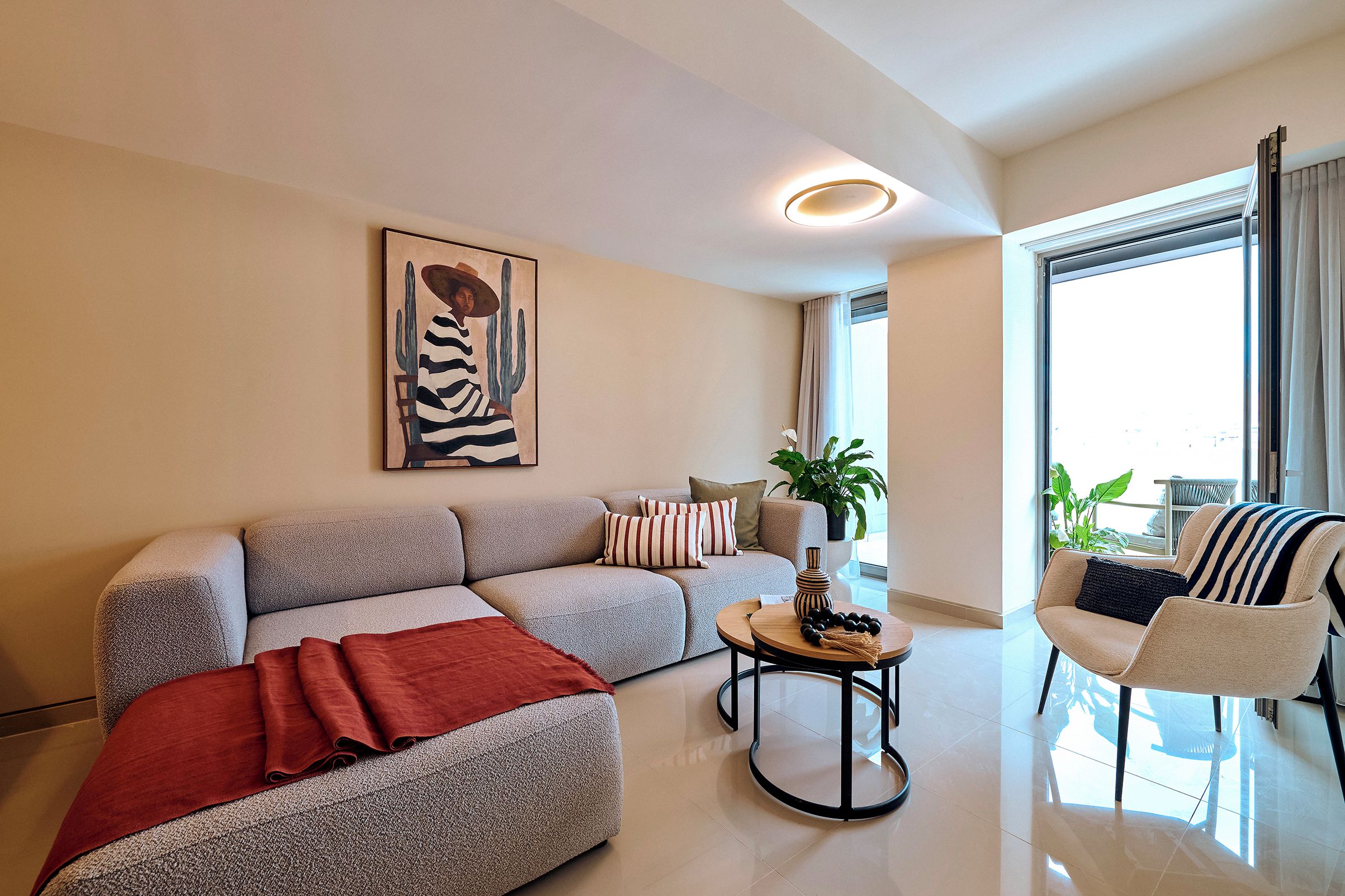 Een moderne woonkamer met een bank, fauteuil, salontafel en kunstwerk.