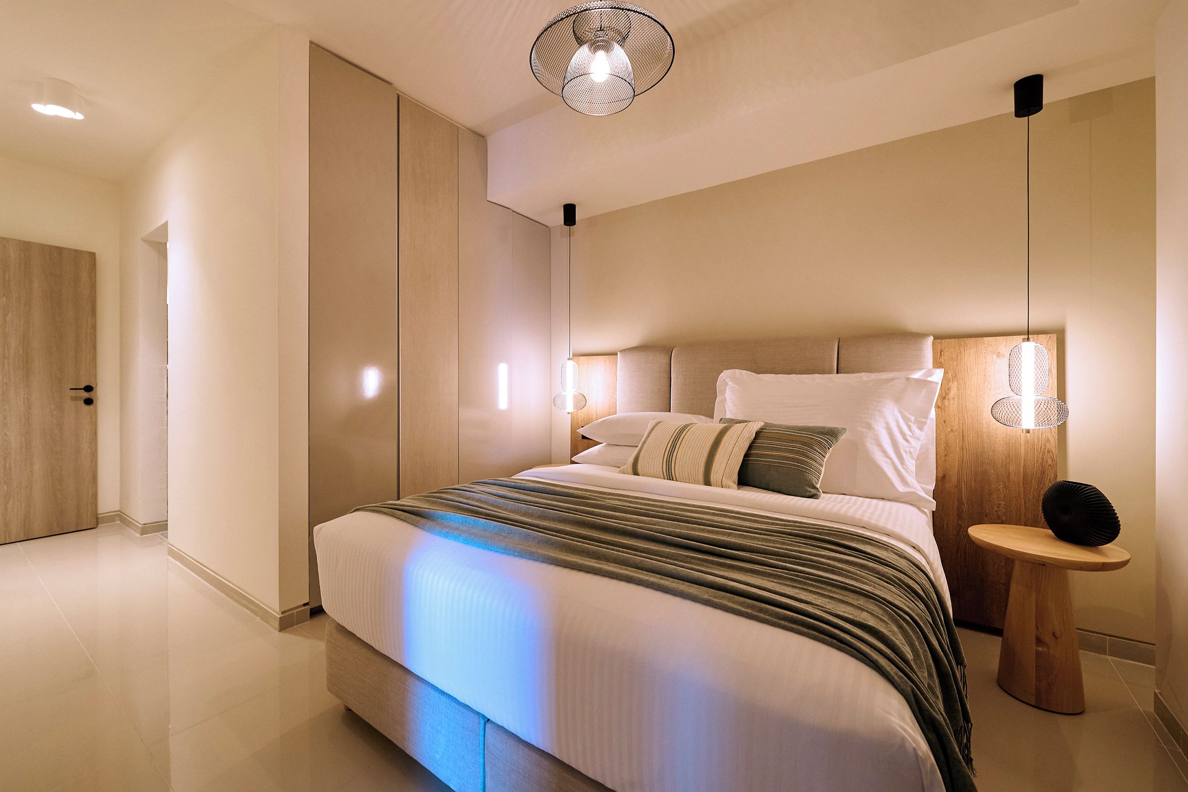 Un dormitorio moderno con una cama grande, mesitas de noche y una lámpara colgante.