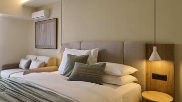 A modern hotel room with a bed, bedside table, and a wall-mounted air conditioner.