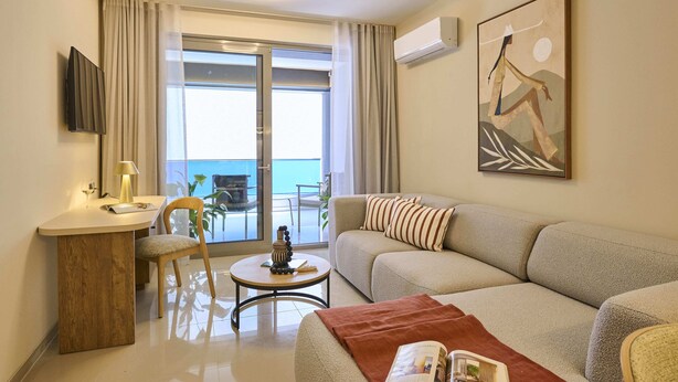 A modern living room with a sofa, a small table, a chair, a TV, and a painting on the wall. - Zeus Piraeus Grand (Piraeus)