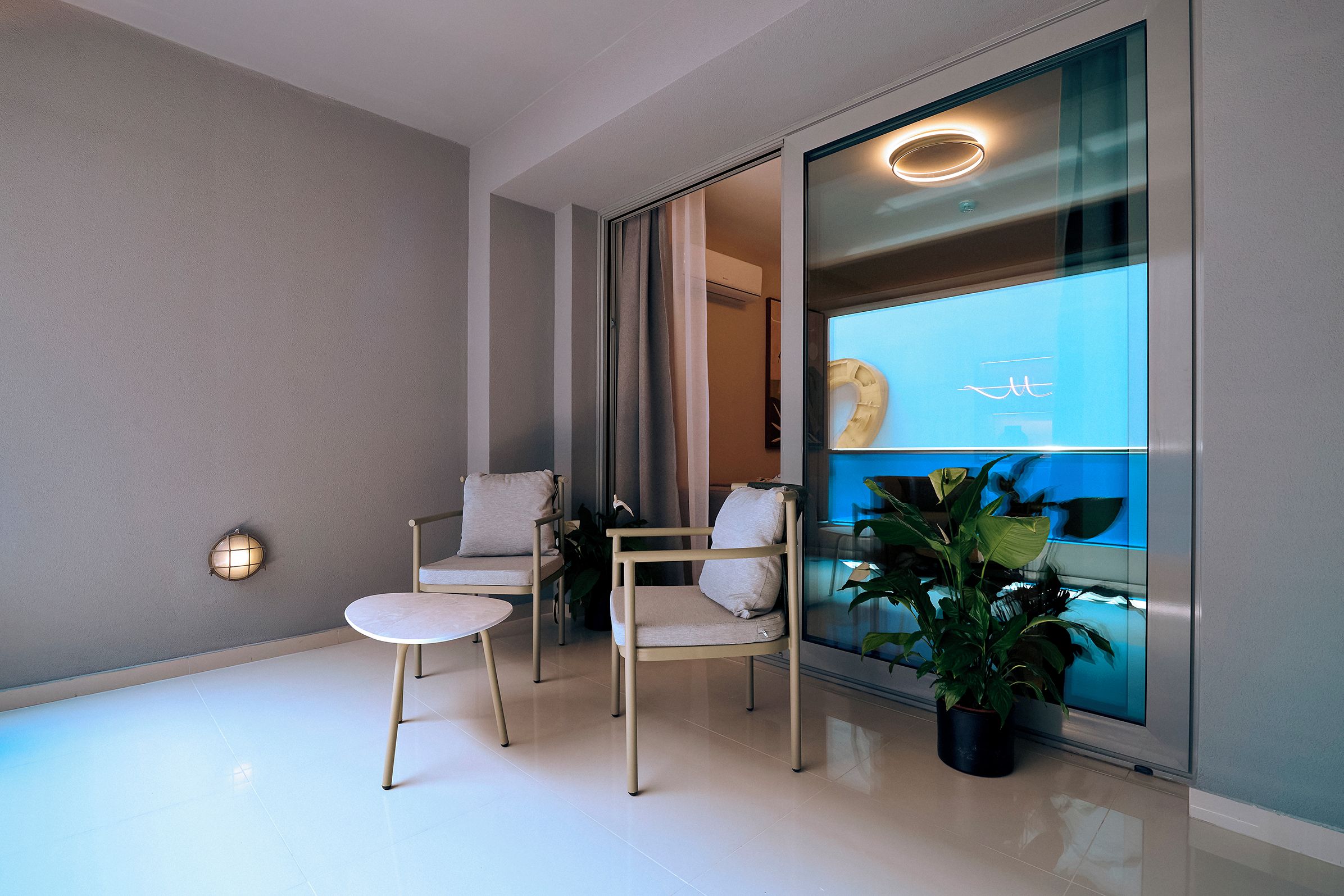 A modern interior with a glass partition, two chairs, a small table, and a potted plant.