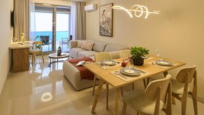 A modern living room with a dining area, a sofa, a coffee table, and a view to the outside. - Zeus Piraeus Grand (Piraeus)