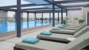 A rooftop pool area with lounge chairs and a glass balustrade. - Zeus Piraeus Grand (Piraeus)