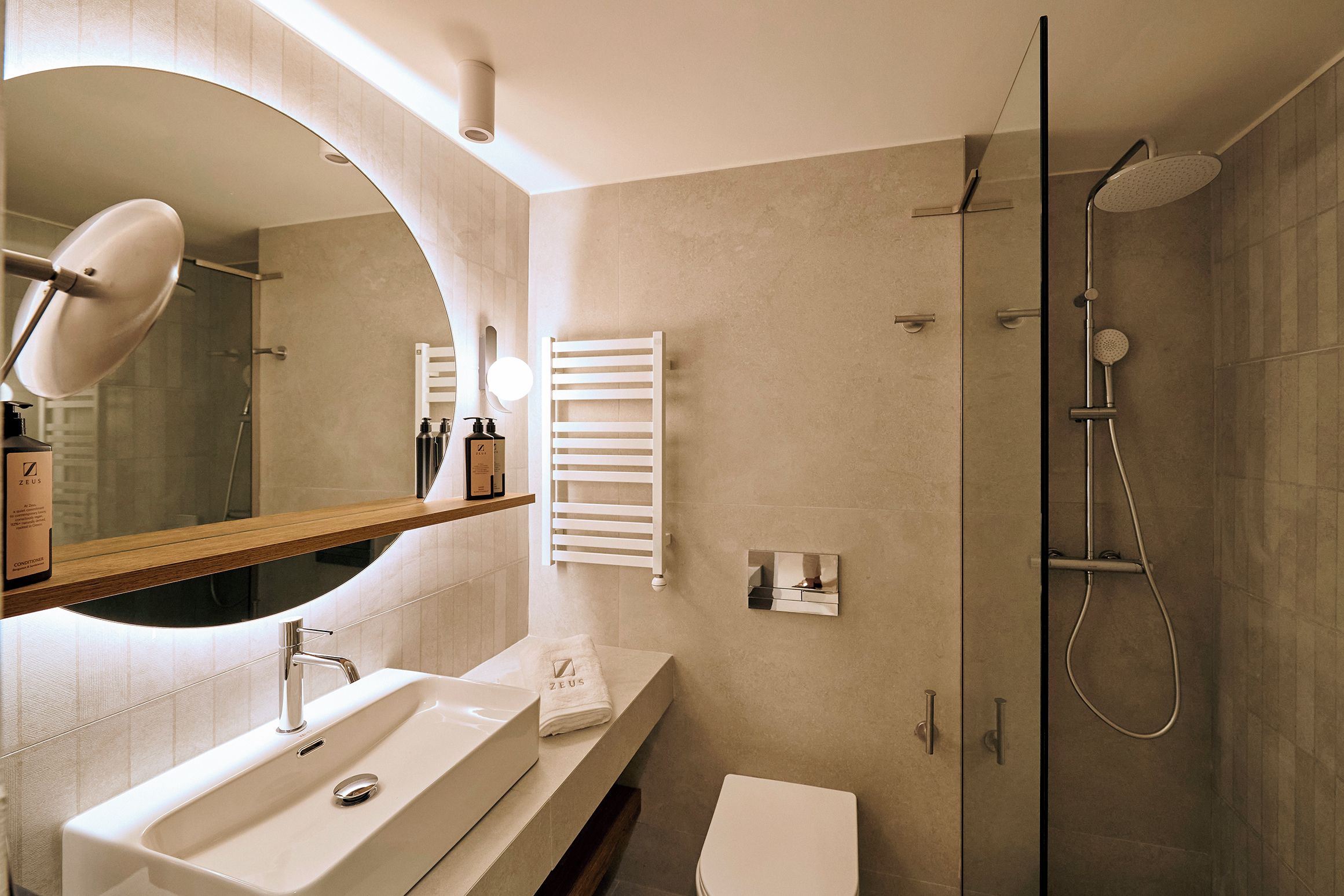 A modern bathroom with a large mirror, a sink, a toilet, and a shower.